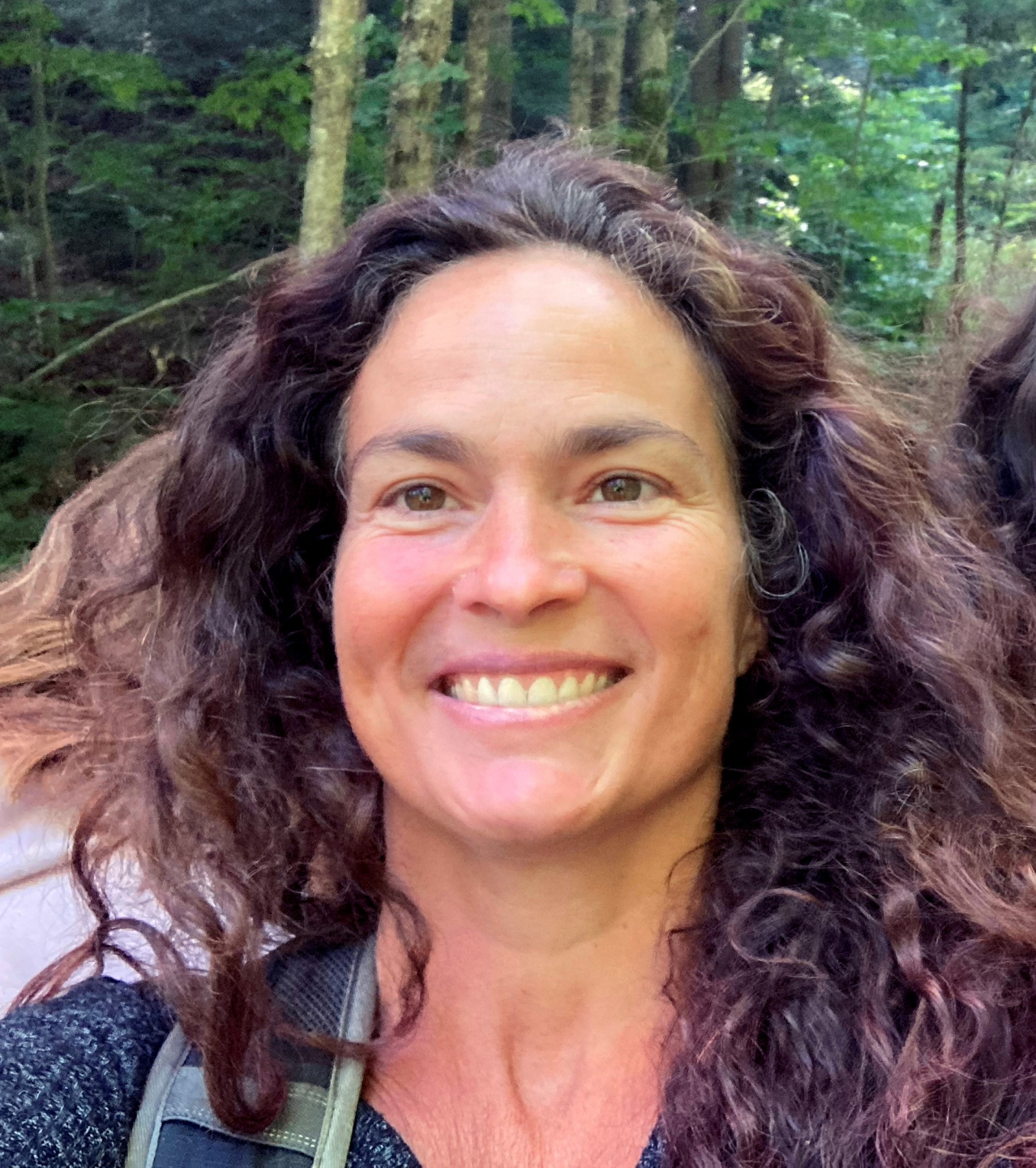 A dark-haired woman smiles.