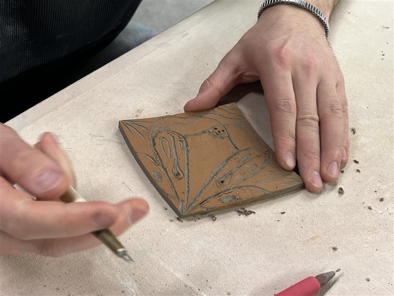 A person carving a clay tile.
