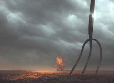 A large public artwork in the shape of a 3-pronged pitchfork on the top of a grassy prairie with thick cloudy skies